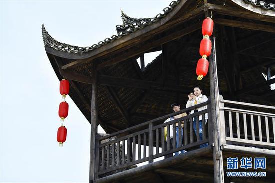  游客在重慶市武隆區(qū)黃鶯鄉(xiāng)復興村的觀景樓上欣賞田園景色（2019年3月28日攝）。 新華社記者 劉潺 攝